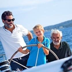 Ein Kind mit seinem Vater und Opa am Steuer einer Yacht