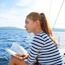 Eine Frau liest ein Buch auf einer Yacht im offenen Meer